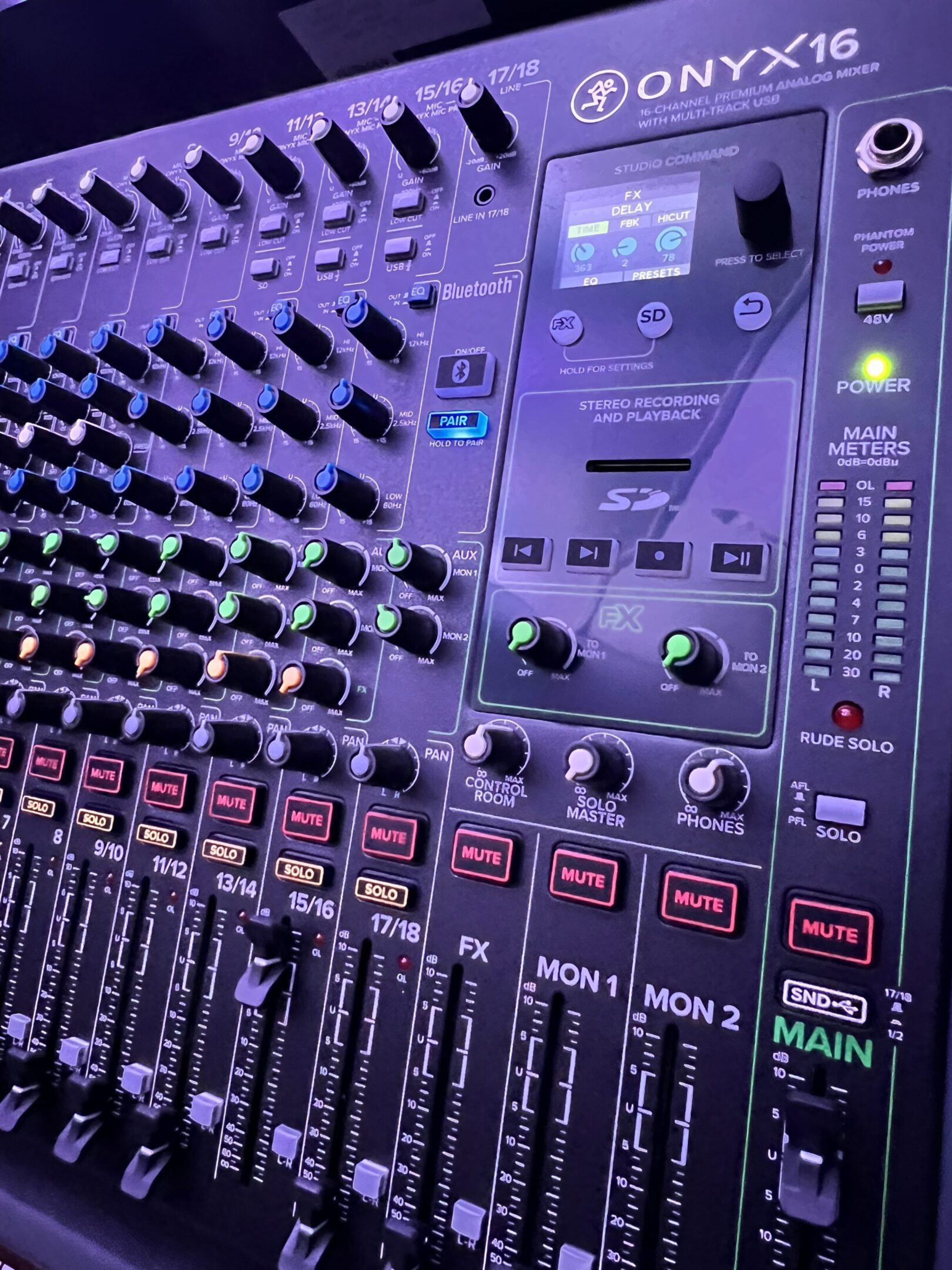 Audio mixer with various knobs and sliders.