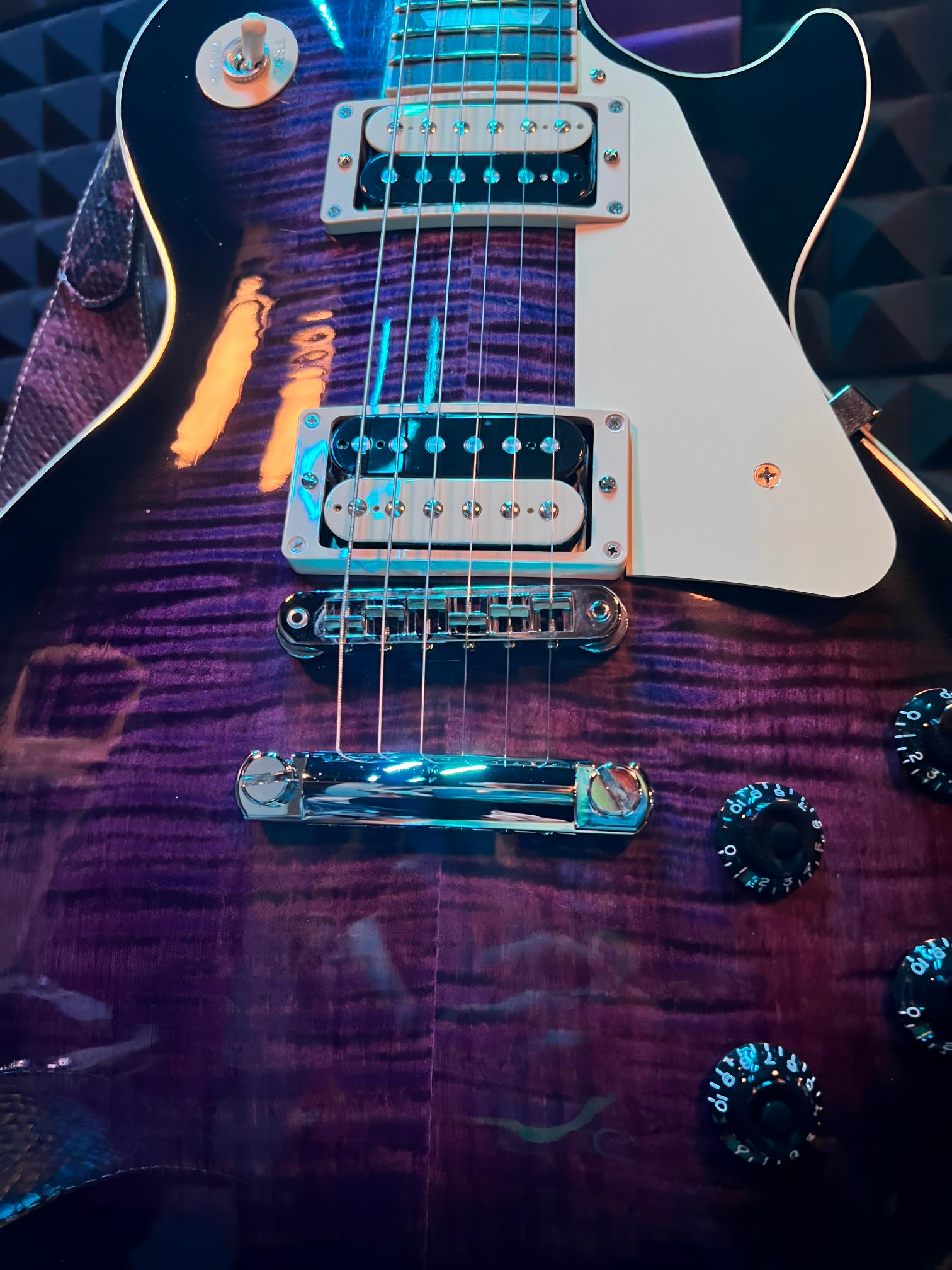 Purple electric guitar with white pickguard.