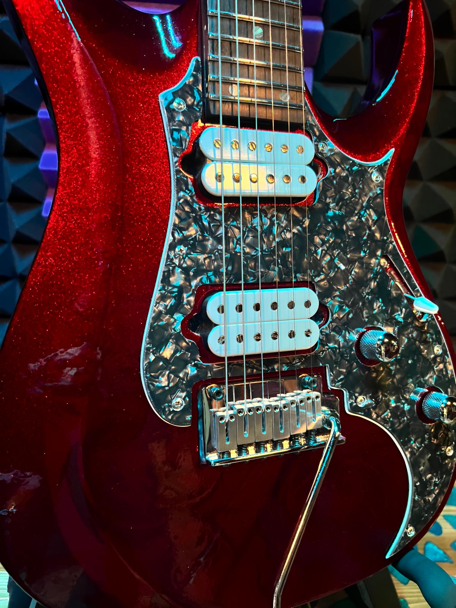 Red electric guitar with intricate pickguard design.