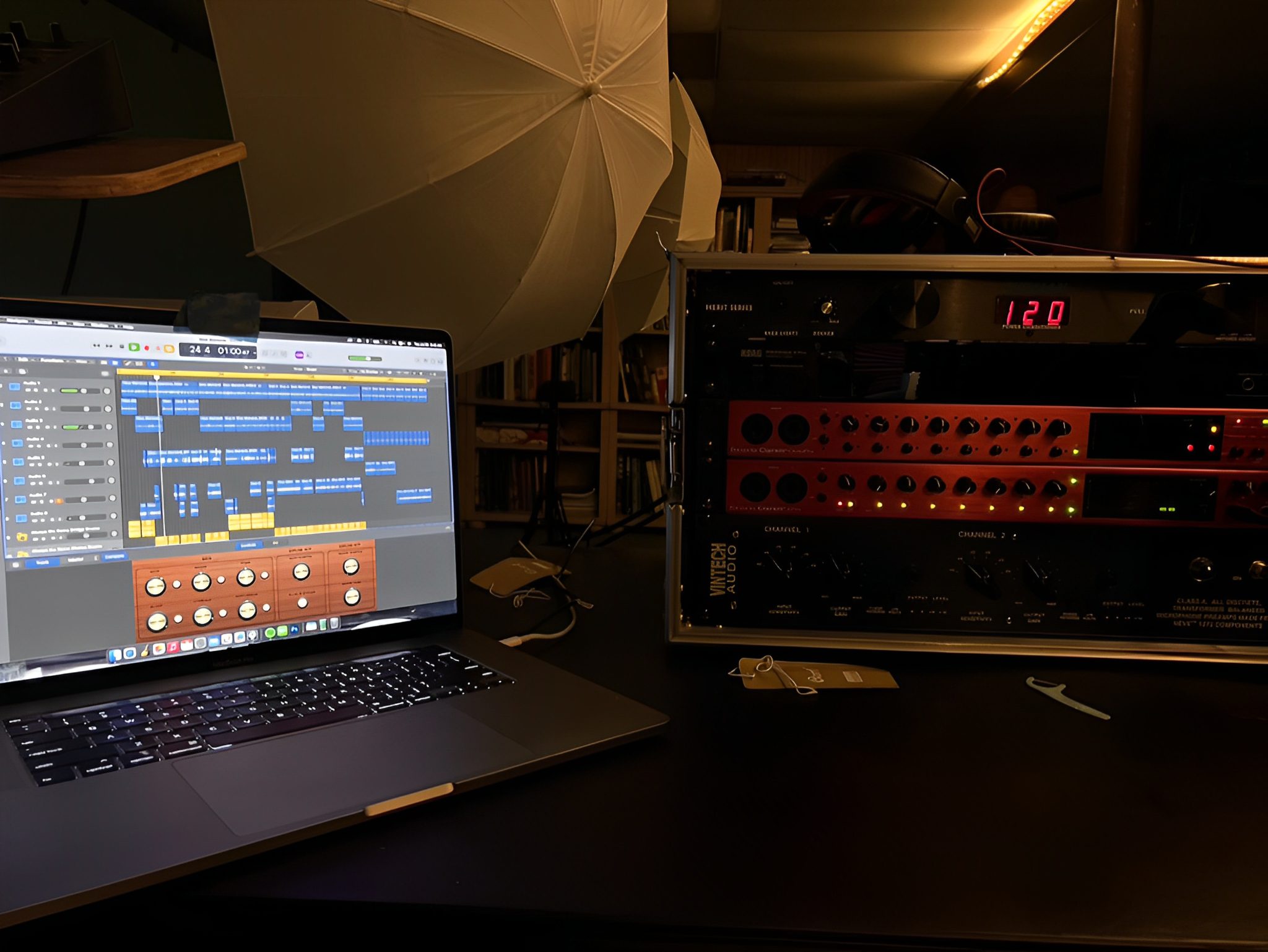 Laptop with audio software beside sound equipment.