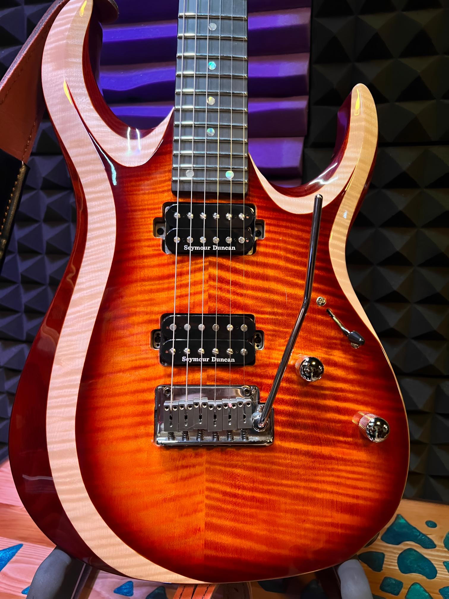 Electric guitar with sunburst finish on stand.